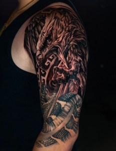 A highly detailed black and grey tattoo featuring a mythical dragon with intricate shading and a realistic snake, inked at Monochrome Tattoo Studio in Fresno, CA.