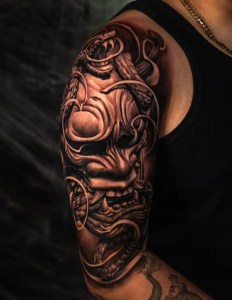 Black and grey samurai mask tattoo sleeve, done at Monochrome Tattoo Studio in Fresno, CA. Featuring detailed shading and linework, crafted by the best tattoo artist in Fresno.
